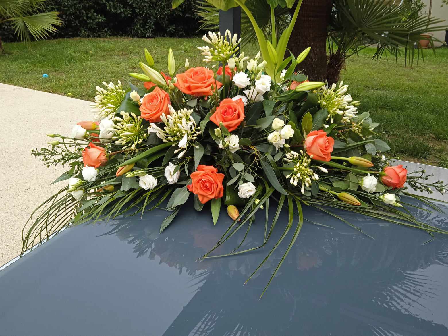 composition funéraire raquette de fleurs blanche et roses orange.